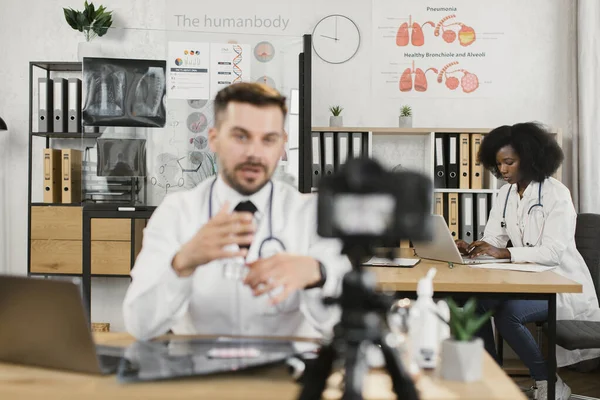 Медсестра с ноутбуком во время записи видео врачом на камеру — стоковое фото