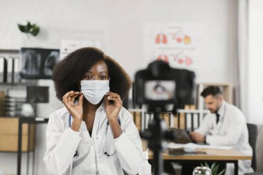 Vlog kaydı sırasında yüz maskesi takmayı gösteren doktor