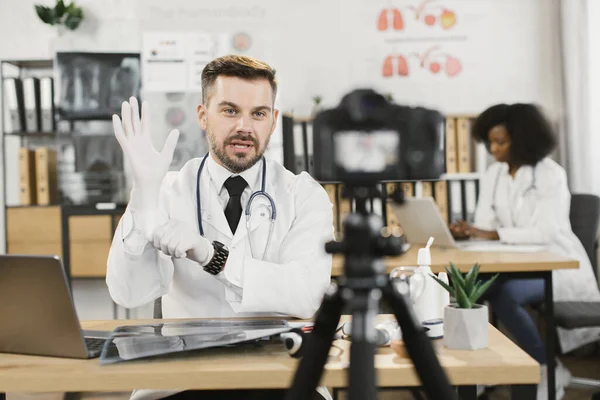 Doktor eldiven takıyor ve kamerada konuşuyor. — Stok fotoğraf