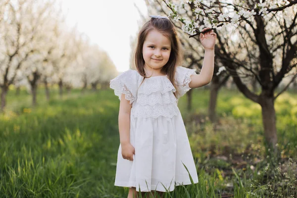 사과나무가 피어 있는 정원에서 포즈를 취하는 사랑 스러운 어린이 — 스톡 사진