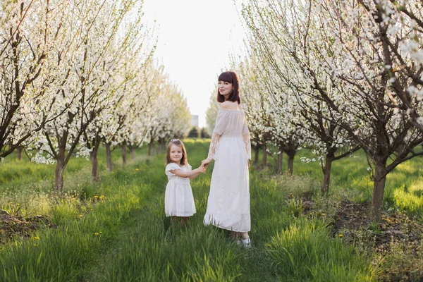 幸せな母とともに娘ポージング間の開花リンゴの木 — ストック写真