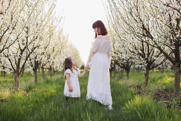 春の果樹園で手をつないでいる母と娘 — ストック写真