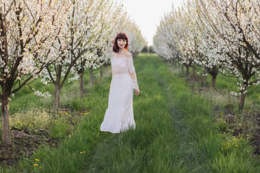 Olumlu kadın çiçek açan elma bahçesinde tek başına yürüyor.