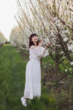 Göz kamaştırıcı kadın elma ağaçlarının çiçeğinin tadını çıkarıyor.