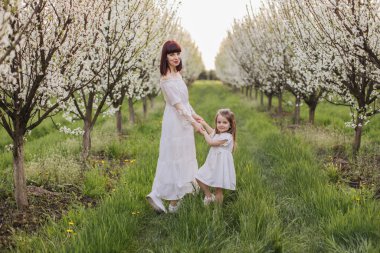 Anne ile kızı çiçek açan bahçede eğleniyor.