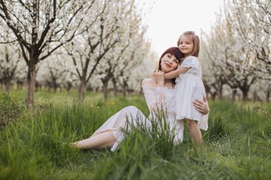 Annesiyle birlikte çiçek açan bahçede kucaklaşan kızı.