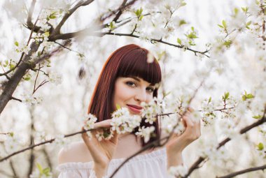 Çiçek açan elma ağacının altında duran muhteşem kadın.