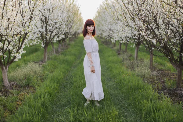 Femme positive marchant seule parmi le jardin de pommes en fleurs — Photo