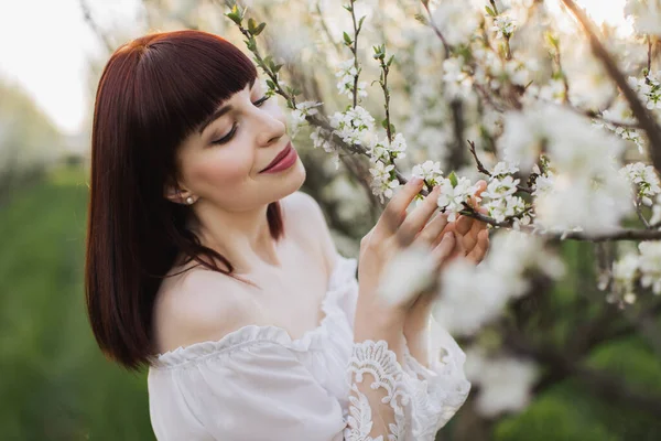 Femme sensuelle en robe blanche posant parmi le jardin de printemps — Photo