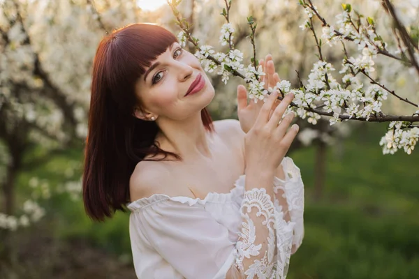 Femme en robe blanche debout près du pommier en fleurs — Photo