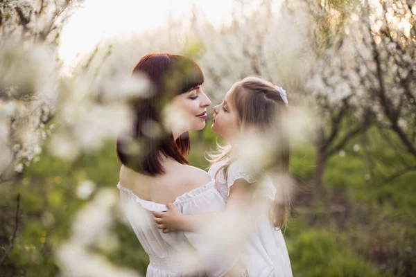 Прихильна мати тримає дочку серед квітучого саду — стокове фото