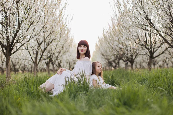 春の庭に座っている娘と母 — ストック写真