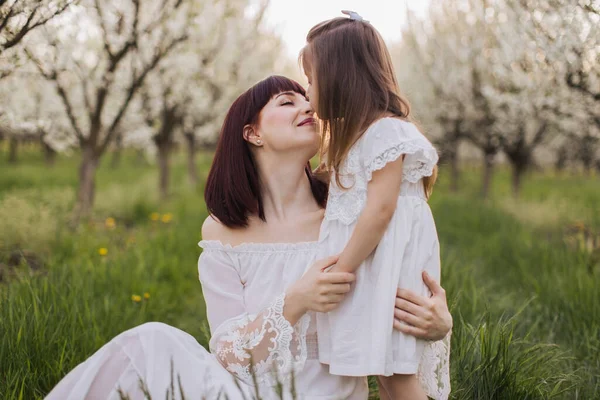 Mãe afetuosa beijando e abraçando filha no jardim — Fotografia de Stock