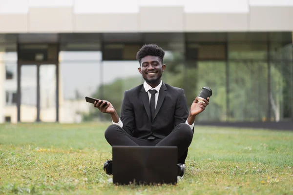 Jeune homme d'affaires africain méditant dehors après le travail devant le bâtiment de l'entreprise — Photo