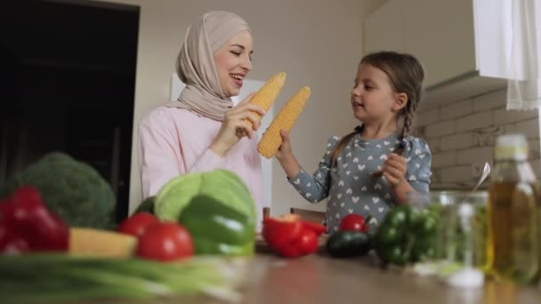 Muslimská matka a malá předškolní dcera se baví při boji pomocí kukuřičné klasy