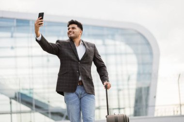 Hintli iş adamı arkadaşına akıllı telefondan video çekiyor ve selam veriyor.