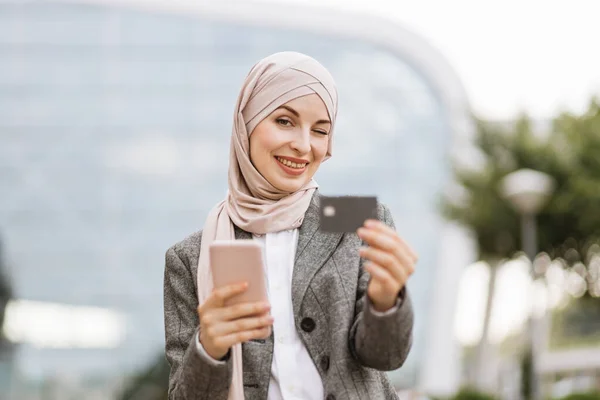 Mujer árabe en pañuelo en la cabeza caminando por la calle con llevar café y teléfono — Foto de Stock