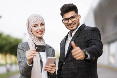 Çok ırklı çift havaalanı terminalinin önünde kredi kartıyla online alışveriş yapıyor..