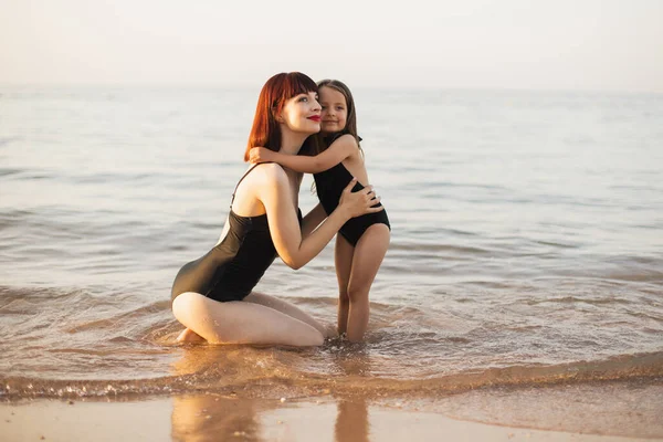 Giovane madre e la sua ragazza godendo la vista sull'oceano e rilassarsi in spiaggia in una giornata di sole — Foto Stock