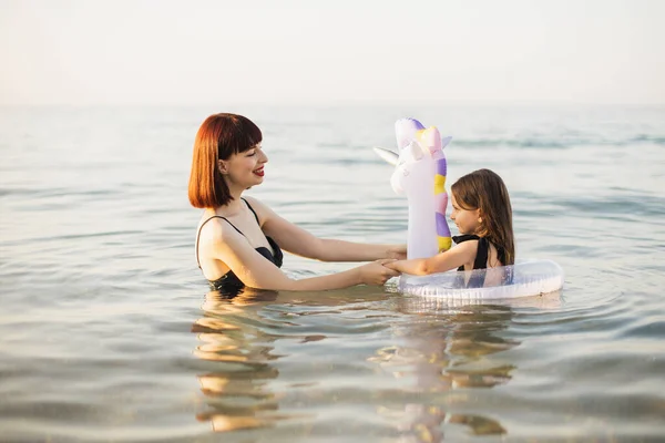 Bella madre che tiene bambino figlia giocattolo gonfiabile galleggiante con bambino in trasparente — Foto Stock