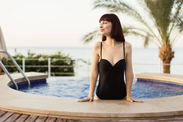 Hübsche Dame im Schwimmbad mit Palme im Hintergrund — Stockfoto