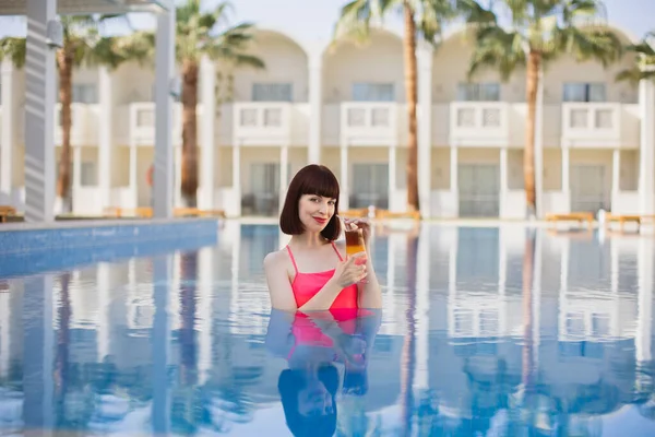 Hübsche junge Dame mit Drink im Pool, genießt die Sommerferien — Stockfoto