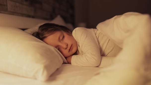 Mignonne petite fille enfant dort dans le lit, tandis que sa maman ajuster la couverture et embrasser son poussin — Video