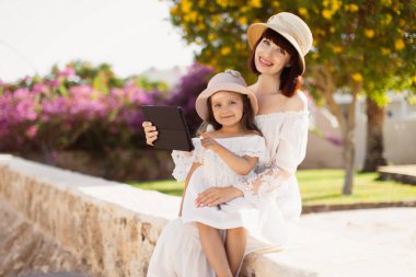 Güneşli bir günde tablet bilgisayar kullanan güzel bir anne ve küçük tatlı bir kız.