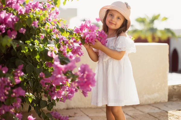 Retrato de uma menina bonito e bonito em um fundo de flores rosa florescendo de árvore tropical. — Fotografia de Stock