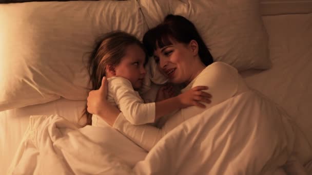Belle famille, mère et fille, couchée au lit et prête à dormir — Video
