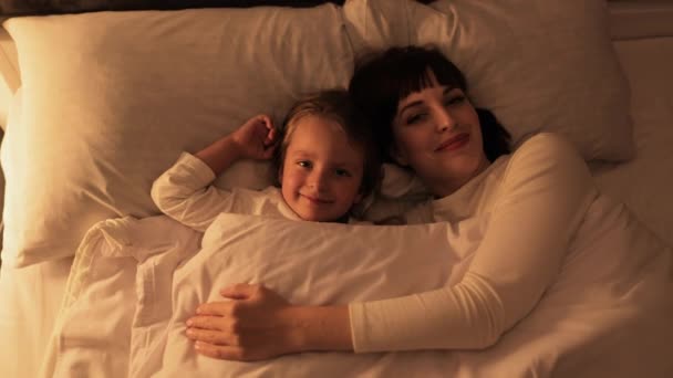 Krásná rodina, matka a dcera, ležící v posteli a připraveni jít spát — Stock video