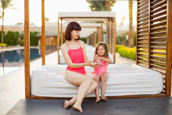 Jeune femme caucasienne en maillot de bain rose appliquant de la crème solaire ou de la crème solaire sur sa main de fille — Photo