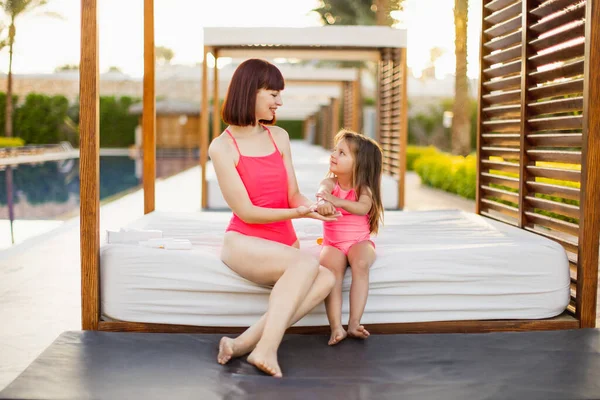 Jeune femme caucasienne en maillot de bain rose appliquant de la crème solaire ou de la crème solaire sur sa main de fille — Photo