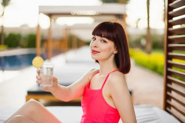 Jolie mannequin féminine en maillot de bain rose, couchée dans le gazebo de plage avec limonade fraîche — Photo