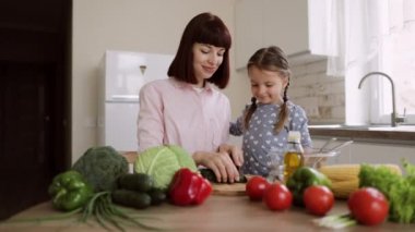 Kafkasyalı anne küçük anaokulu kızına öğle yemeği için sebze doğramayı öğretiyor.