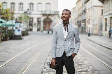 Eski bir fotoğraf makinesiyle caddede duran mutlu Afrikalı adam.
