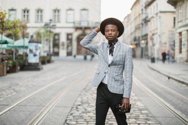 Afrikalı erkek hipster elinde fotoğraf makinesiyle sokakta dikiliyor.