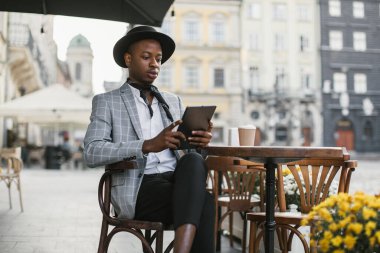 Kafe masasında tablet üzerinde çalışan Afrikalı işadamı