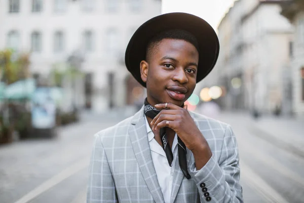 Hombre africano en ropa elegante y sombrero posando en la calle de la ciudad — Foto de Stock