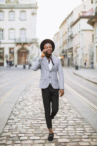 Afrikaanse man loopt op straat en praat op mobiele — Stockfoto