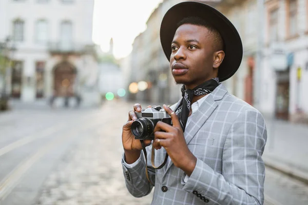 Africano homem tirar foto na câmera retro enquanto caminha — Fotografia de Stock