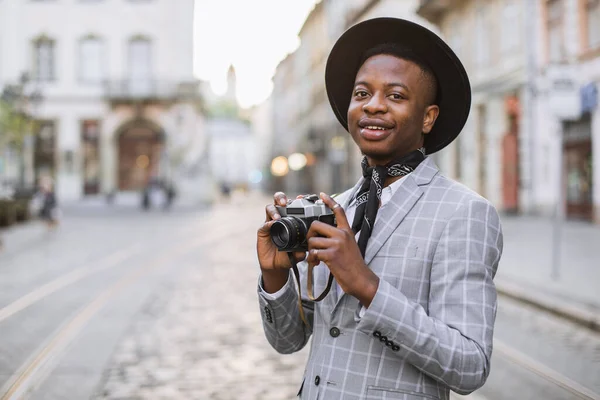 Glimlachende Afrikaanse kerel met behulp van vintage fotocamera buiten — Stockfoto