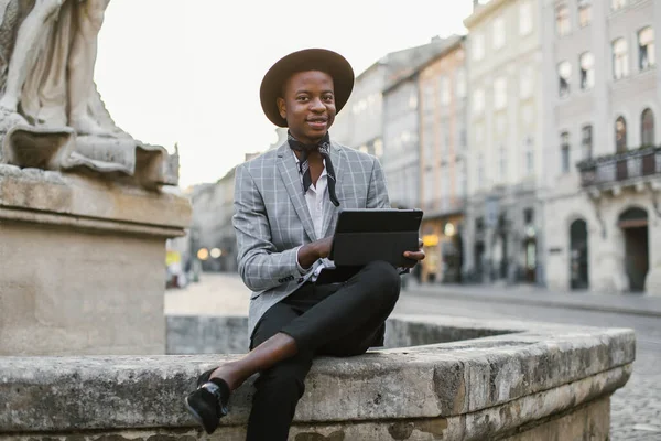 Caddede dijital tablet kullanan yakışıklı Afrikalı adam.