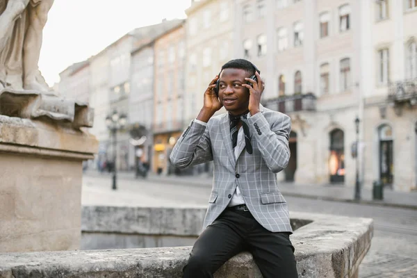 Gelukkig Afrikaans man in koptelefoon luisteren muziek op straat — Stockfoto