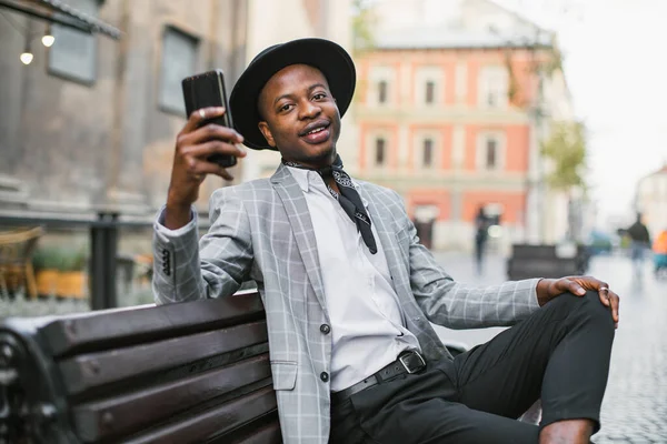 アフリカ人男性とともにスマートフォンを手に屋外で休んで — ストック写真