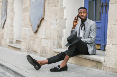 Açık havada akıllı telefon kullanan Afrikalı bir adamın yan görüntüsü