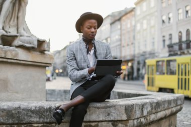 Caddede dijital tablet kullanan yakışıklı Afrikalı adam.