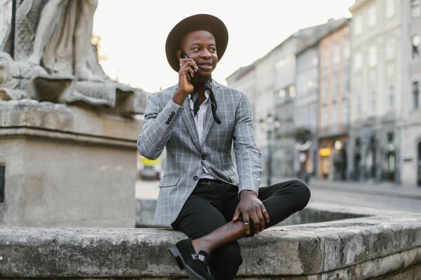 Sorrindo homem africano ter chamada móvel na rua da cidade — Fotografia de Stock