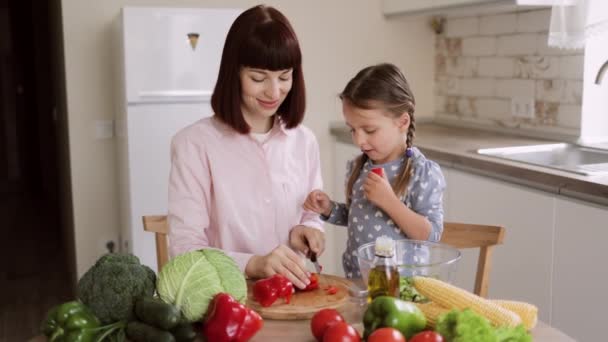 Kaukasiska mor lär lite förskolebarn dotter hugga peppar förbereda sallad för lunch — Stockvideo