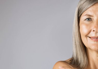 Gri saçlı, pürüzsüz tenli, olgun bir kadının yarım yüzü.